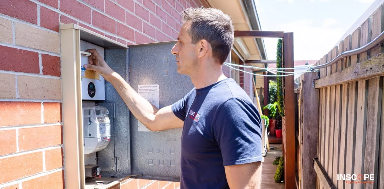 Building inspector examining an electrical switchboard during a pre-purchase property inspection.
