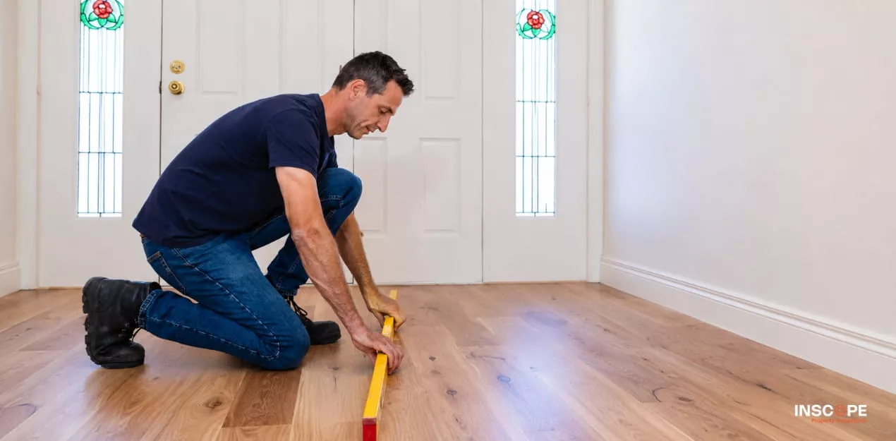 Building inspector checking the level of a timber floor with a spirit level.