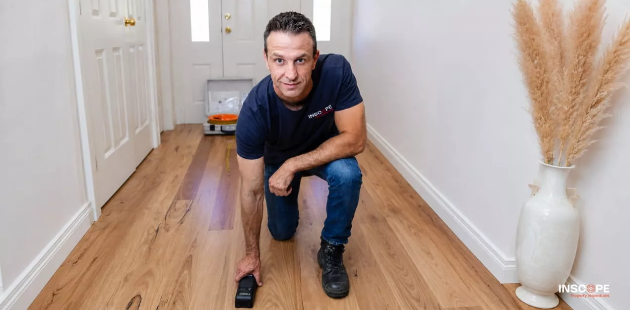 Building inspector checking timber flooring for signs of moisture or timber pest activity.